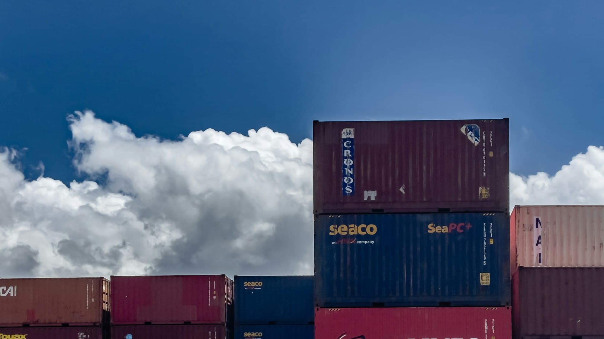 Stacked shipping containers under a blue sky