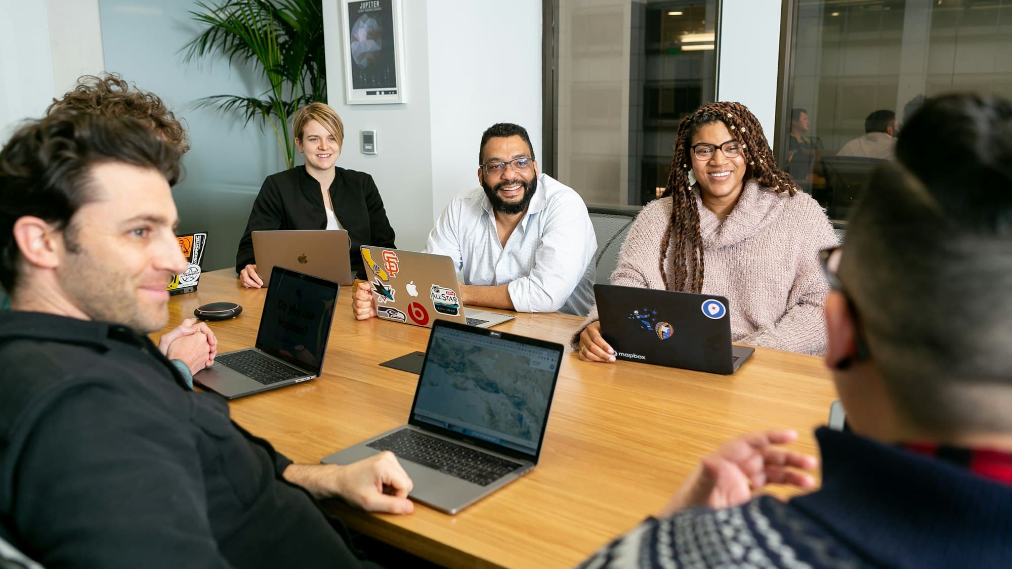 A team meeting around a table with laptops