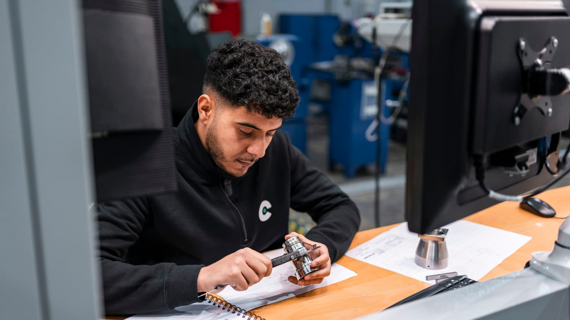 A man carefully measuring a metal component